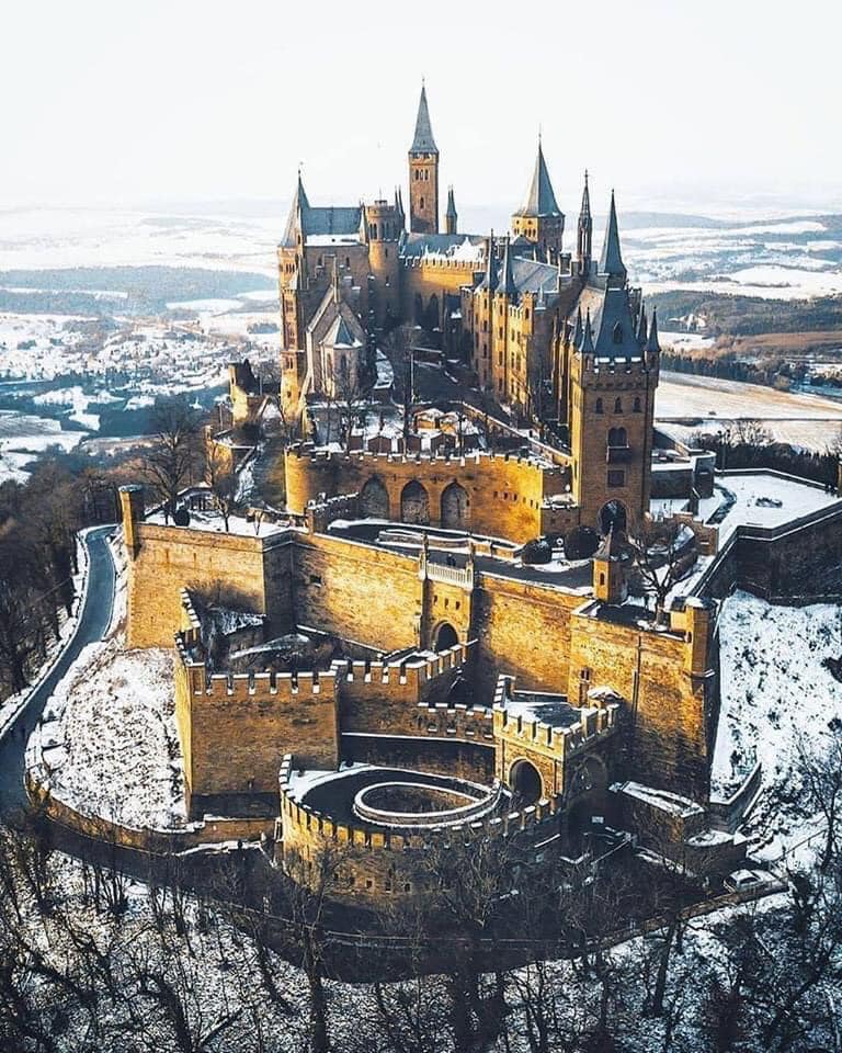 A majestic castle perched on a snowy hilltop with sprawling walls and towers.